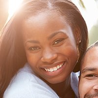 Woman smiling warmly next to the shoulder of a person.